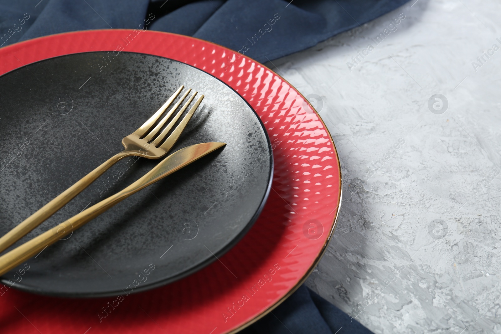 Photo of Elegant ceramic plates and cutlery on light textured table, closeup. Space for text