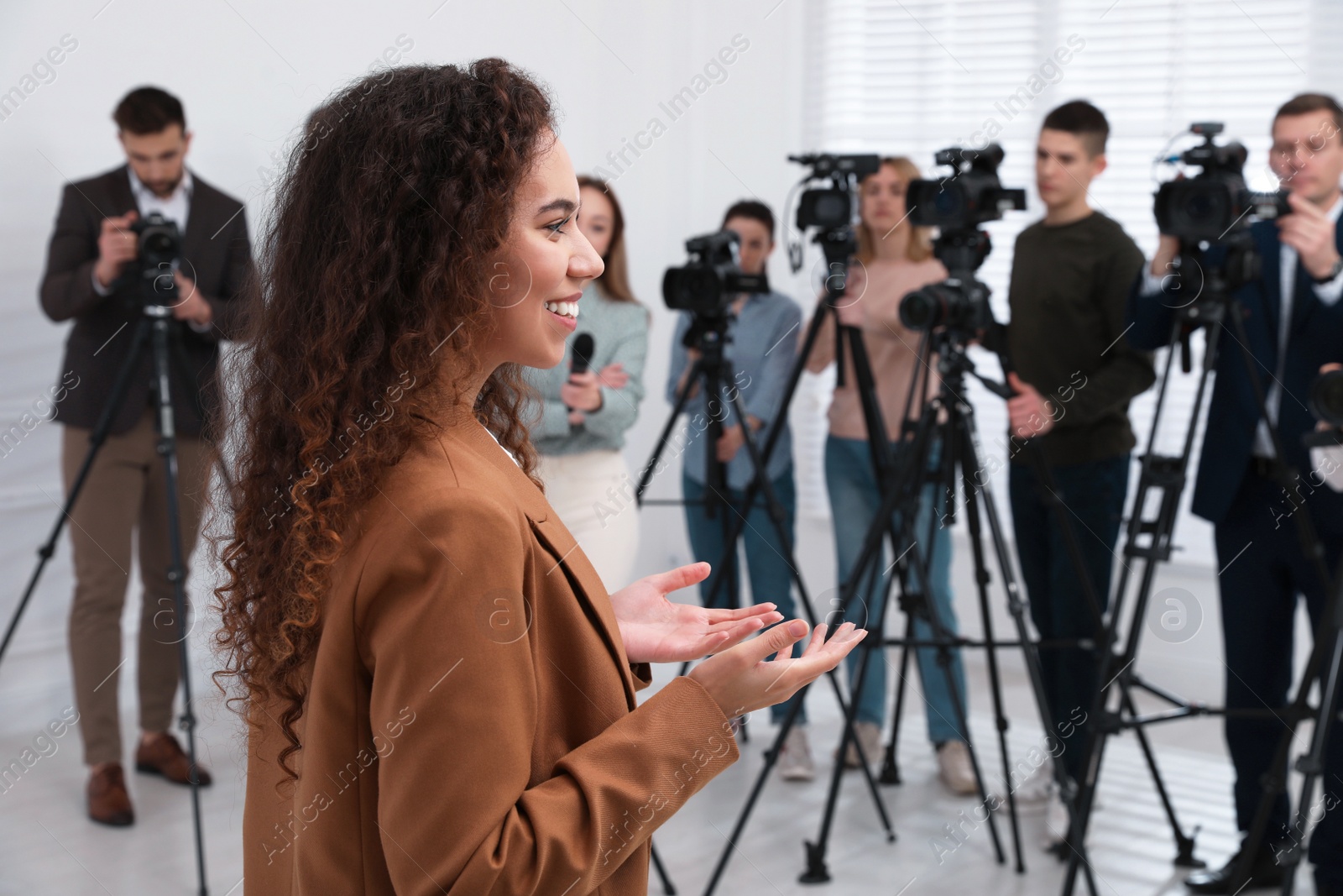 Photo of Happy African American business woman talking to group of journalists indoors