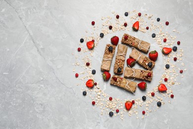 Photo of Tasty granola bars and ingredients on light grey marble table, flat lay. Space for text