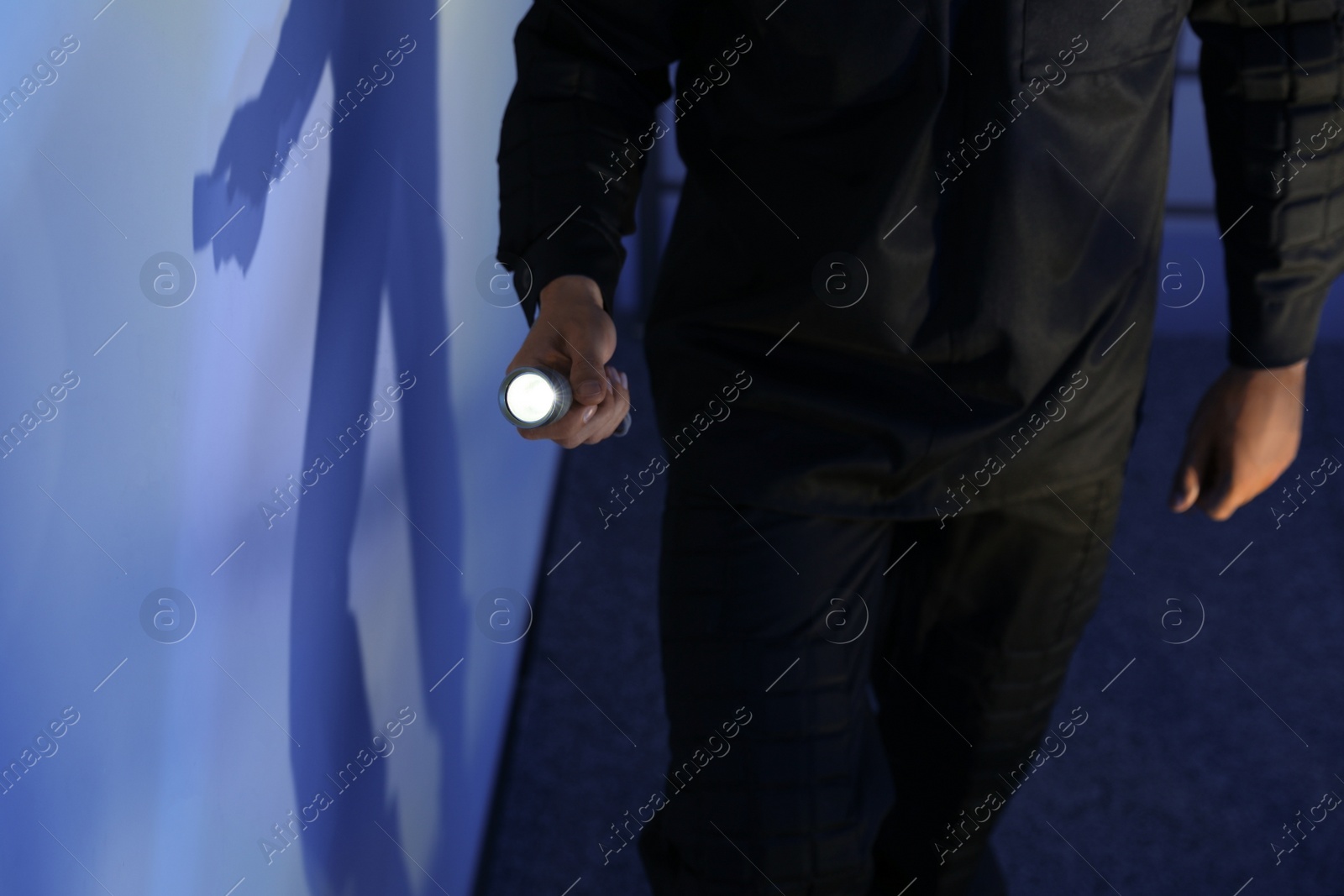 Photo of Male security guard with flashlight in dark room, closeup