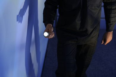 Photo of Male security guard with flashlight in dark room, closeup