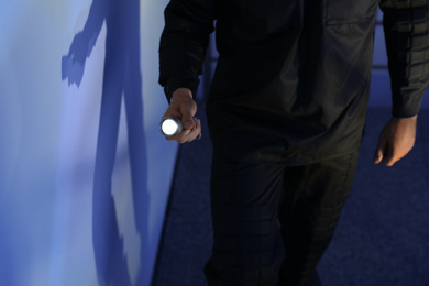 Male security guard with flashlight in dark room, closeup