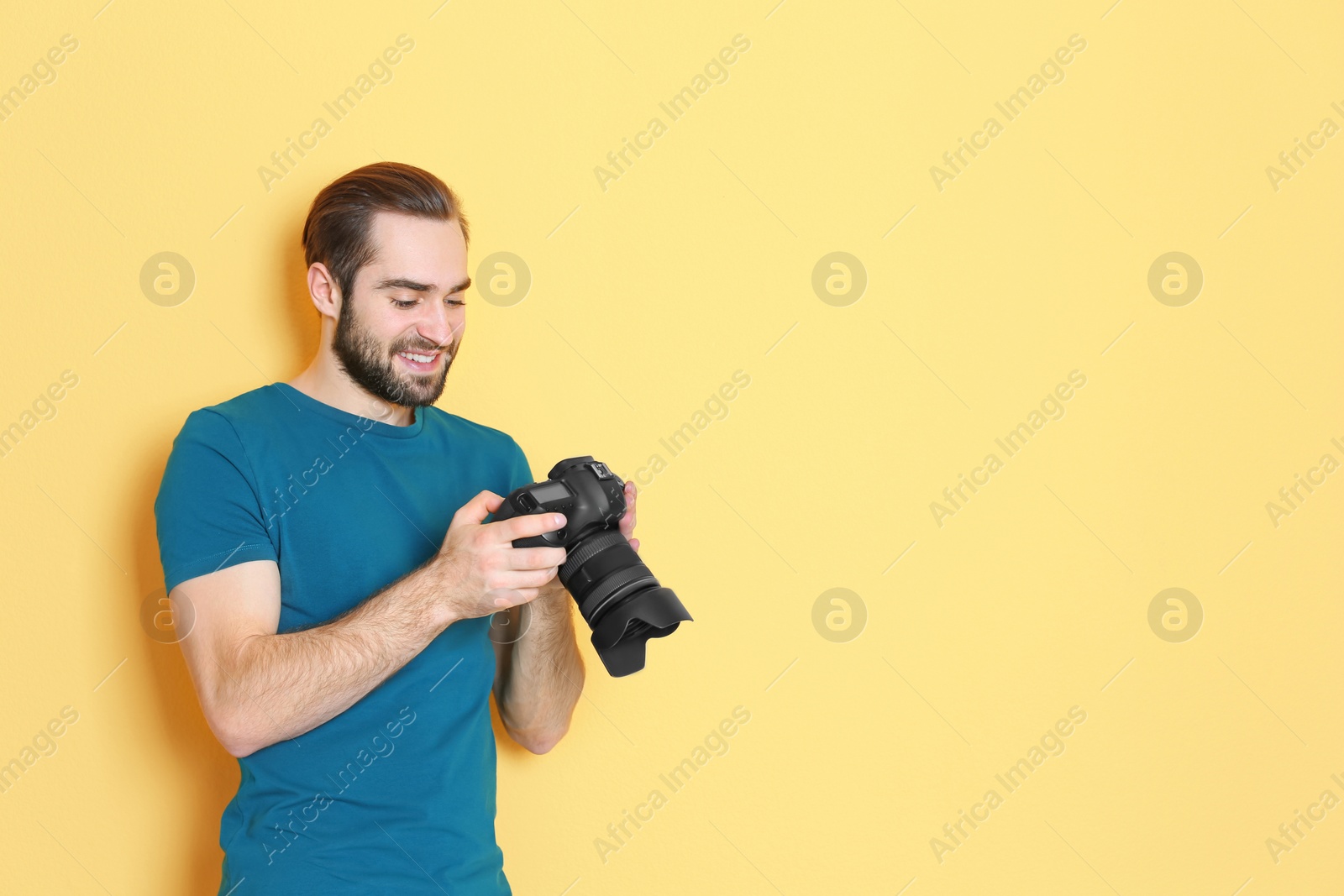 Photo of Young photographer with professional camera on color background
