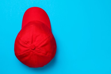 Baseball cap on light blue background, top view. Space for text