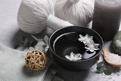 Beautiful composition with herbal massage bags, spa products and flowers on light grey table