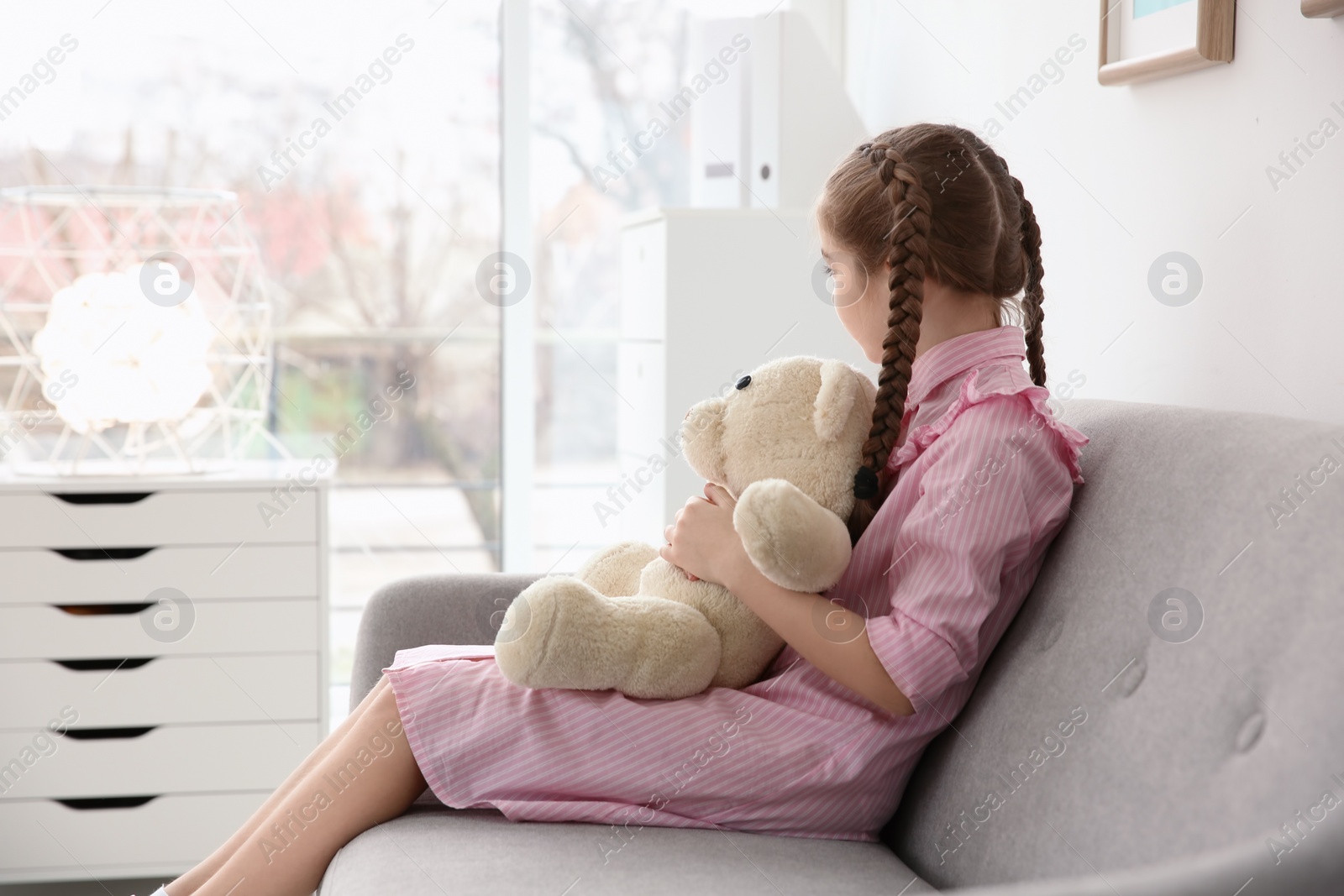 Photo of Little autistic girl sitting on sofa with toy at home