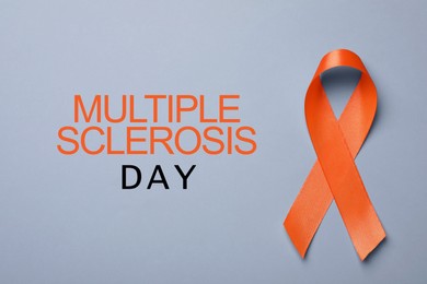 Image of Multiple Sclerosis Awareness Day. Orange ribbon on grey background, top view