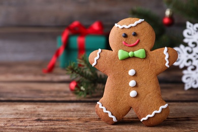 Photo of Gingerbread man on wooden table, closeup. Space for text