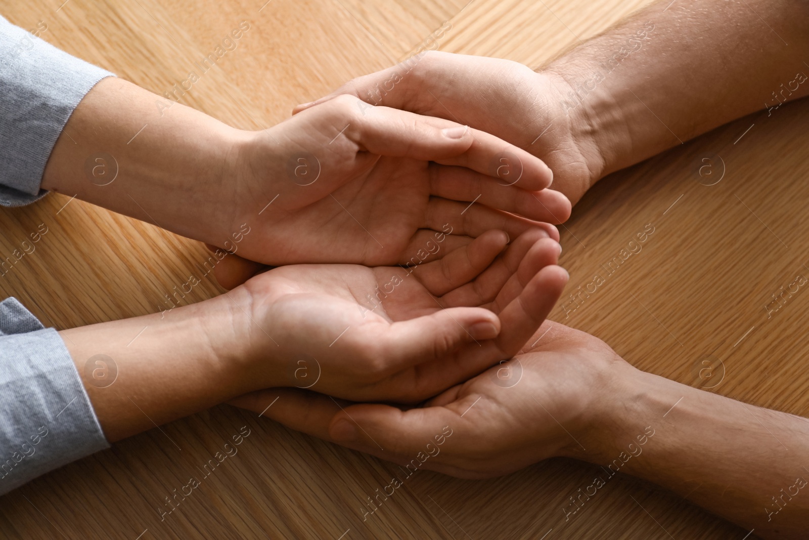 Photo of Young people holding hands on wooden background, top view. Happy family