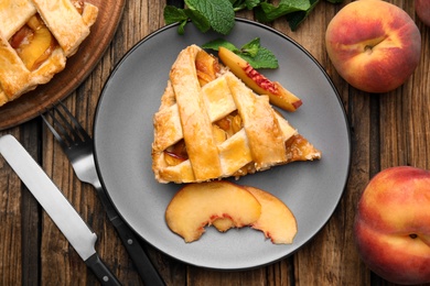 Photo of Delicious fresh peach pie served on wooden table, flat lay