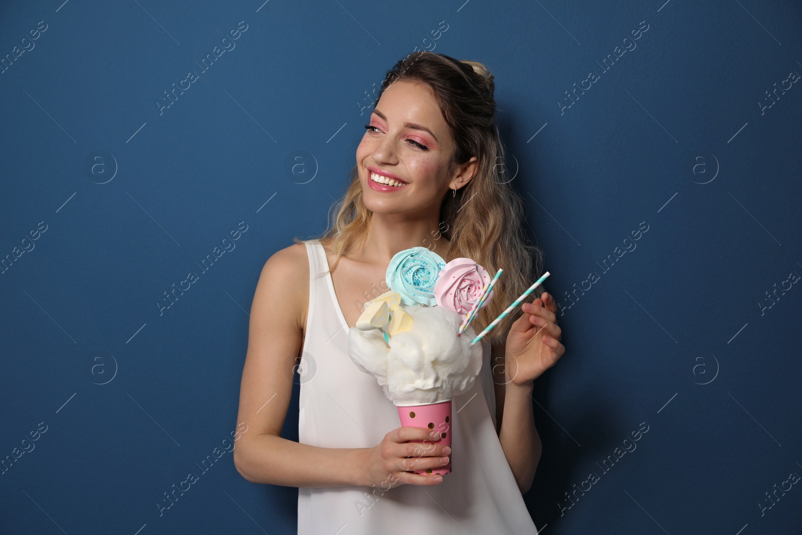 Photo of Portrait of young woman holding cotton candy dessert on blue background