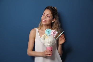 Photo of Portrait of young woman holding cotton candy dessert on blue background