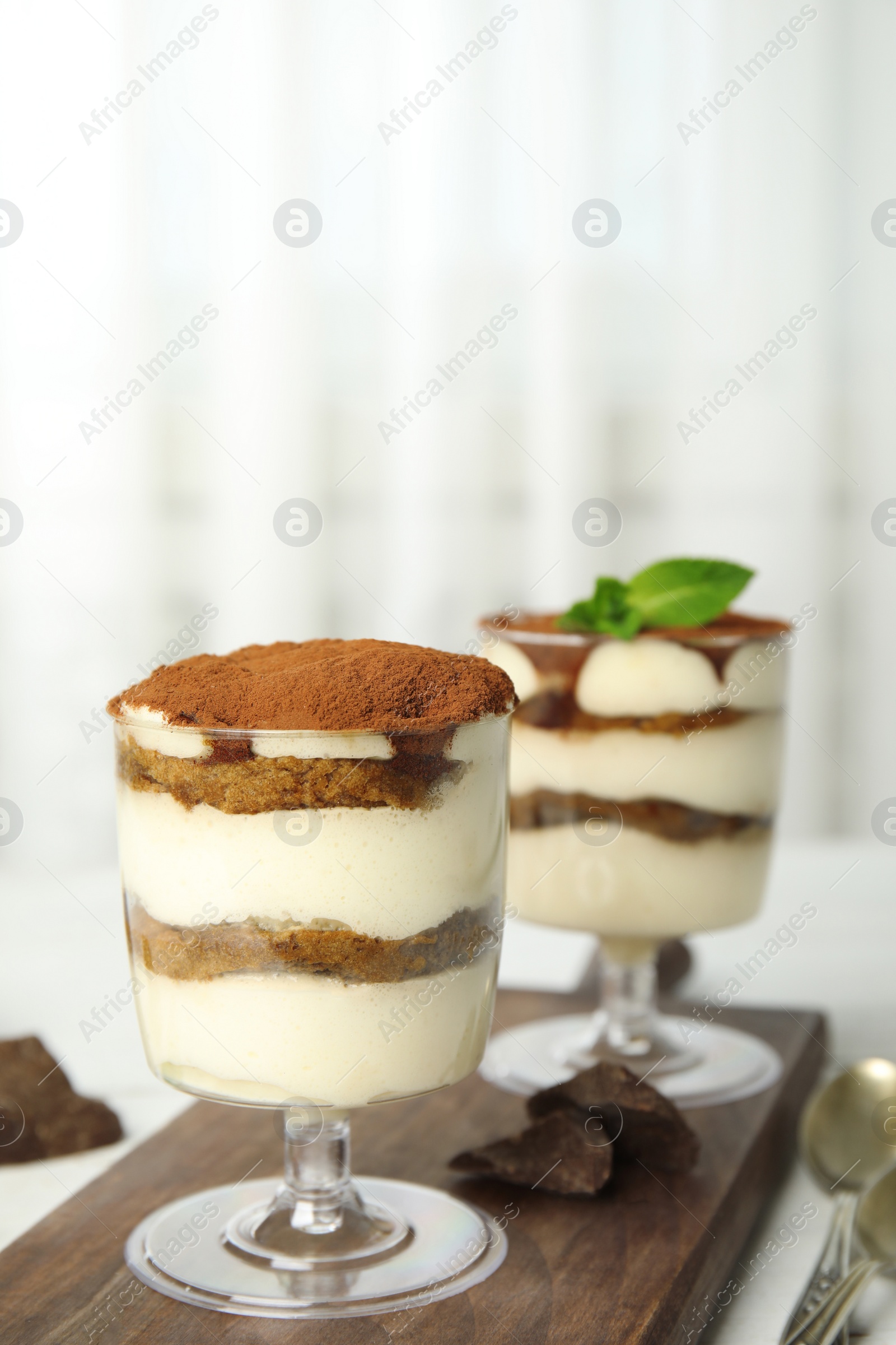 Photo of Composition with two glasses of tiramisu cake and chocolate on table