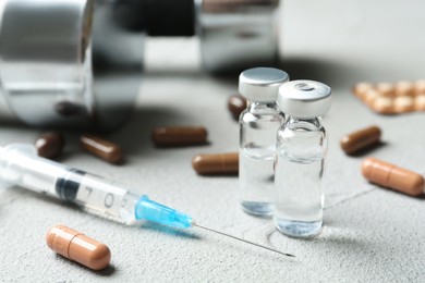 Photo of Different drugs and dumbbells on light grey table. Doping control