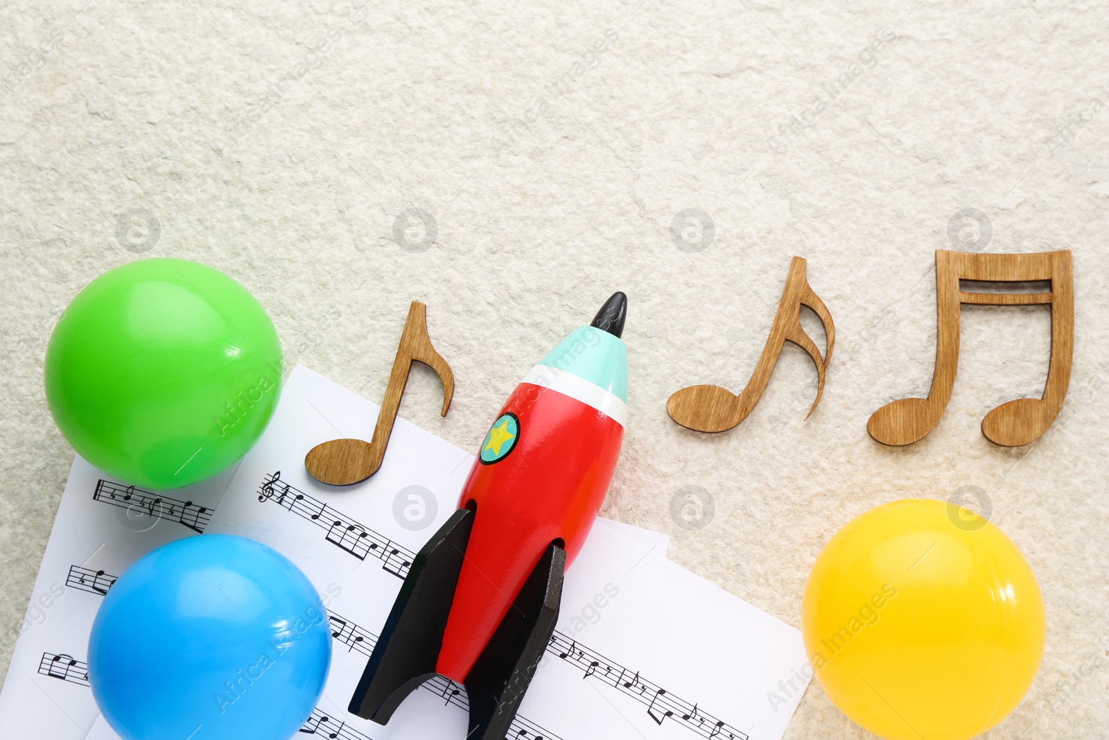 Photo of Wooden notes, music sheets and toys on beige textured background, flat lay with space for text. Baby song concept