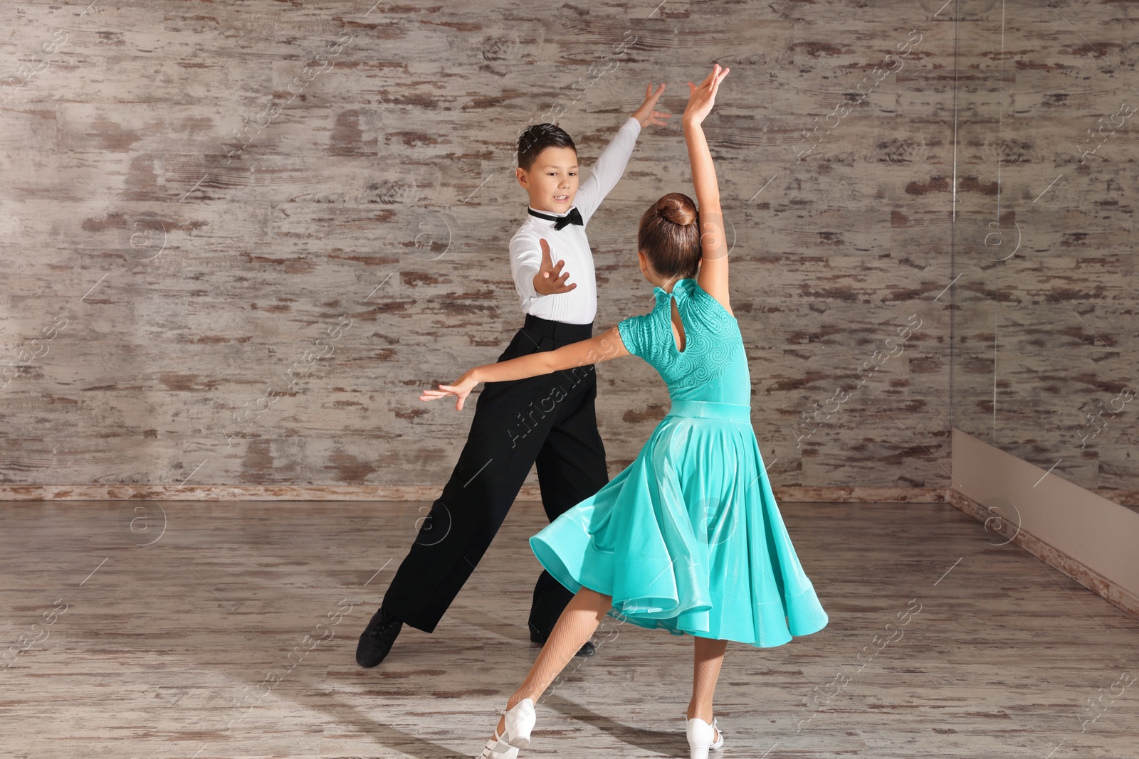 Photo of Beautifully dressed couple of kids dancing together in studio