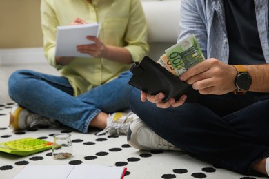 Photo of Young couple counting money on floor at home, closeup