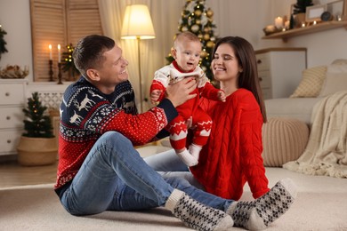 Photo of Happy couple with cute baby in room decorated for Christmas