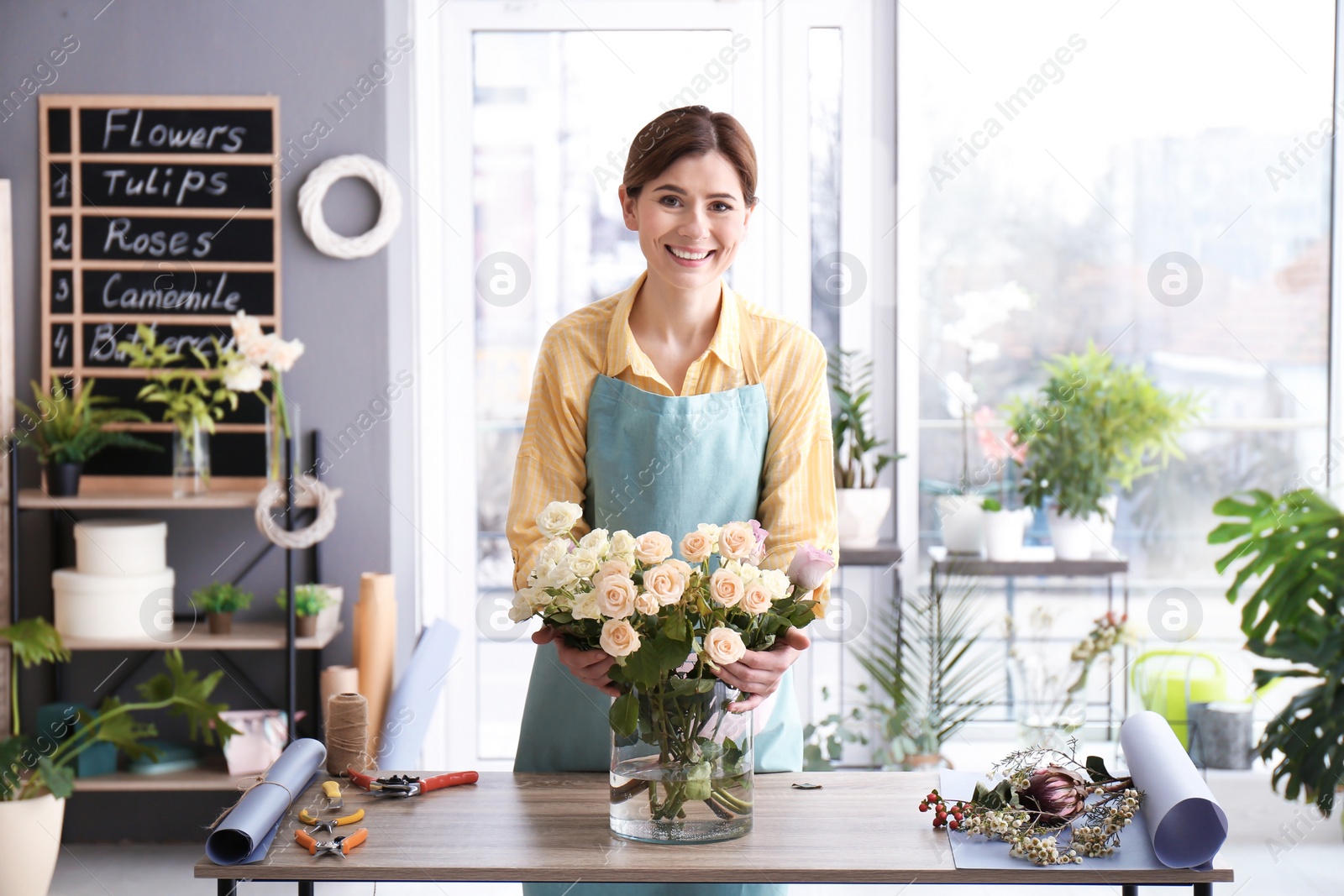 Photo of Female florist with roses at workplace