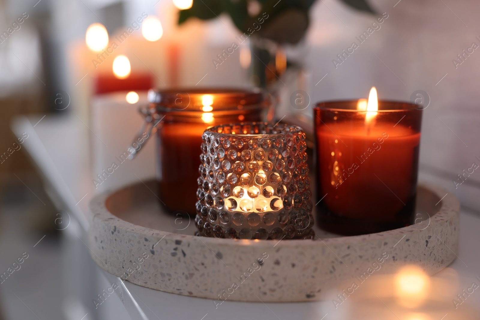 Photo of Burning candles on mantel near white wall indoors