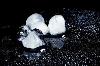 Melting ice cubes on black background. Space for text