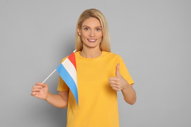 Photo of Woman with flag of Netherlands showing thumb up on light grey background