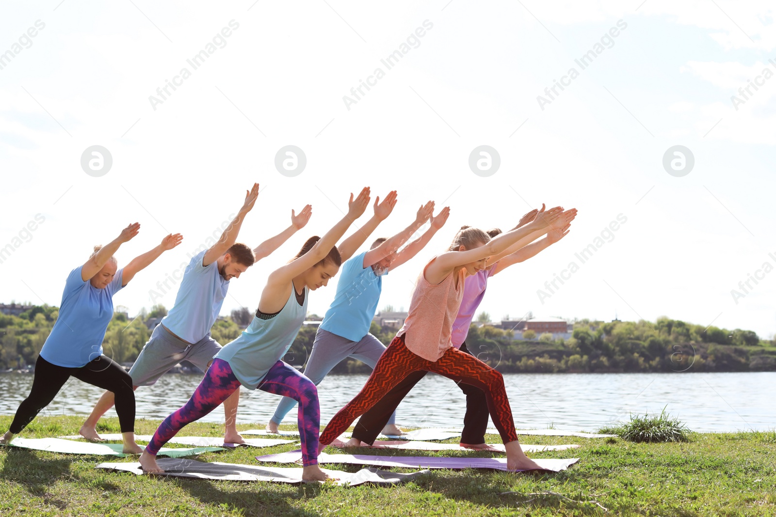 Photo of Group of people practicing yoga near river on sunny day