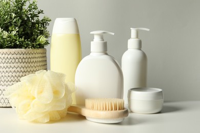 Different bath accessories and houseplant on white table against grey background, closeup