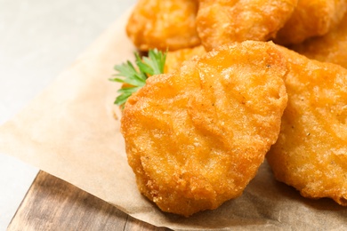 Tasty fried chicken nuggets on light grey table, closeup