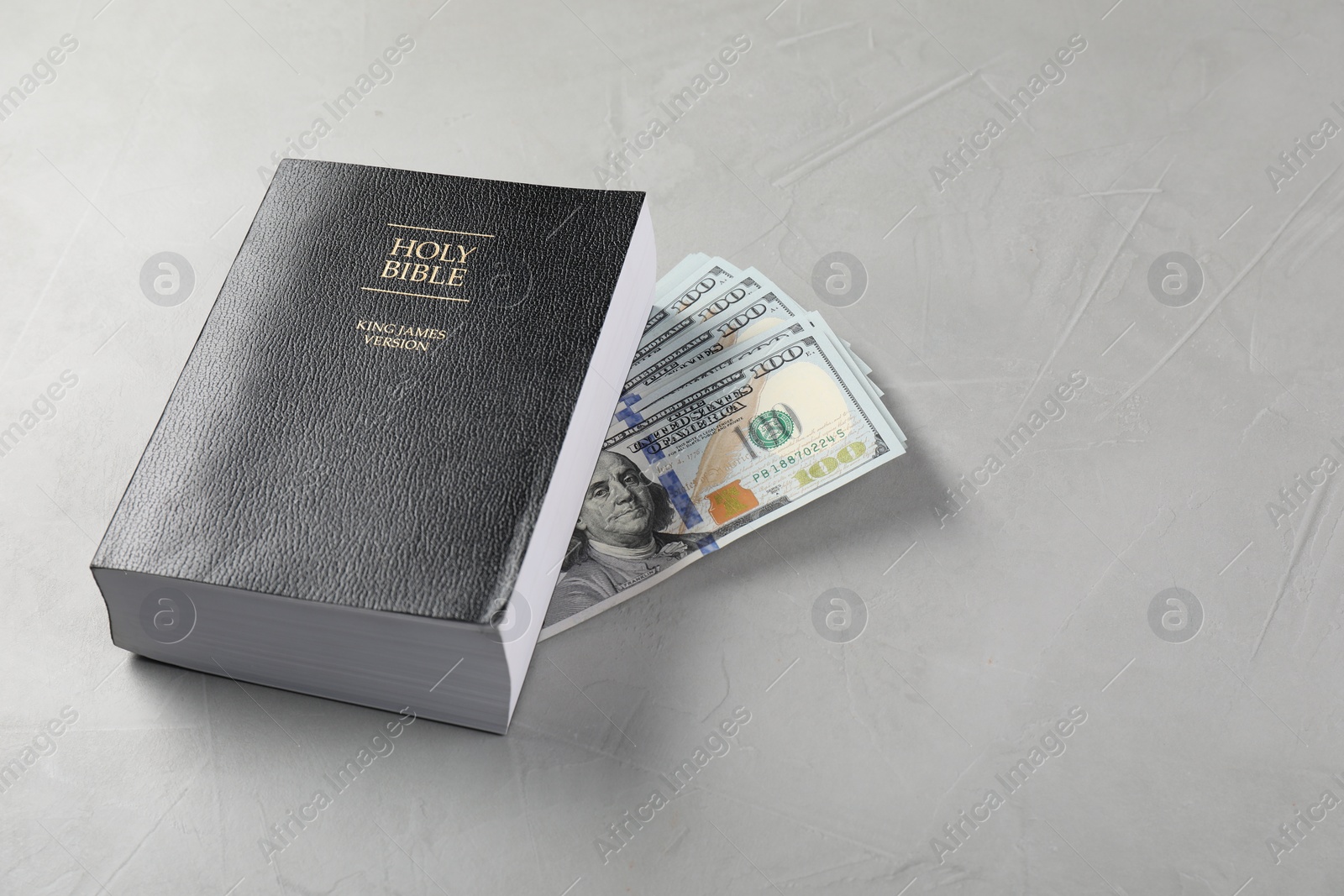 Photo of Holy Bible and money on grey table. Space for text