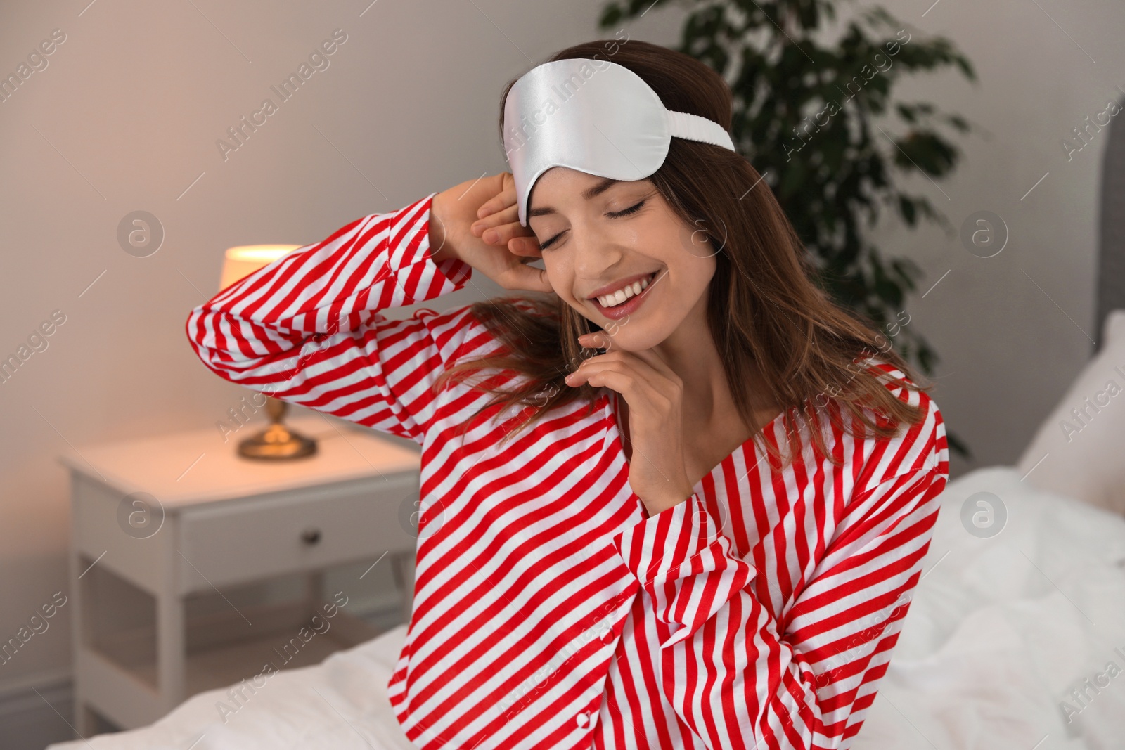 Photo of Beautiful woman wearing pajamas and sleep mask indoors. Bedtime
