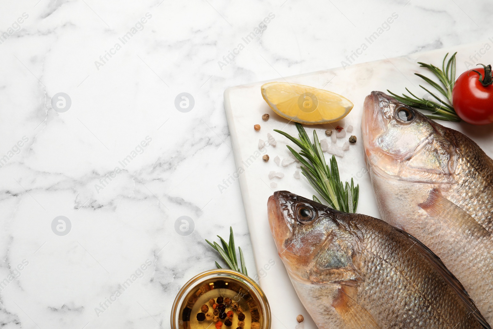 Photo of Fresh raw perches and ingredients on white marble table, flat lay with space for text. River fish
