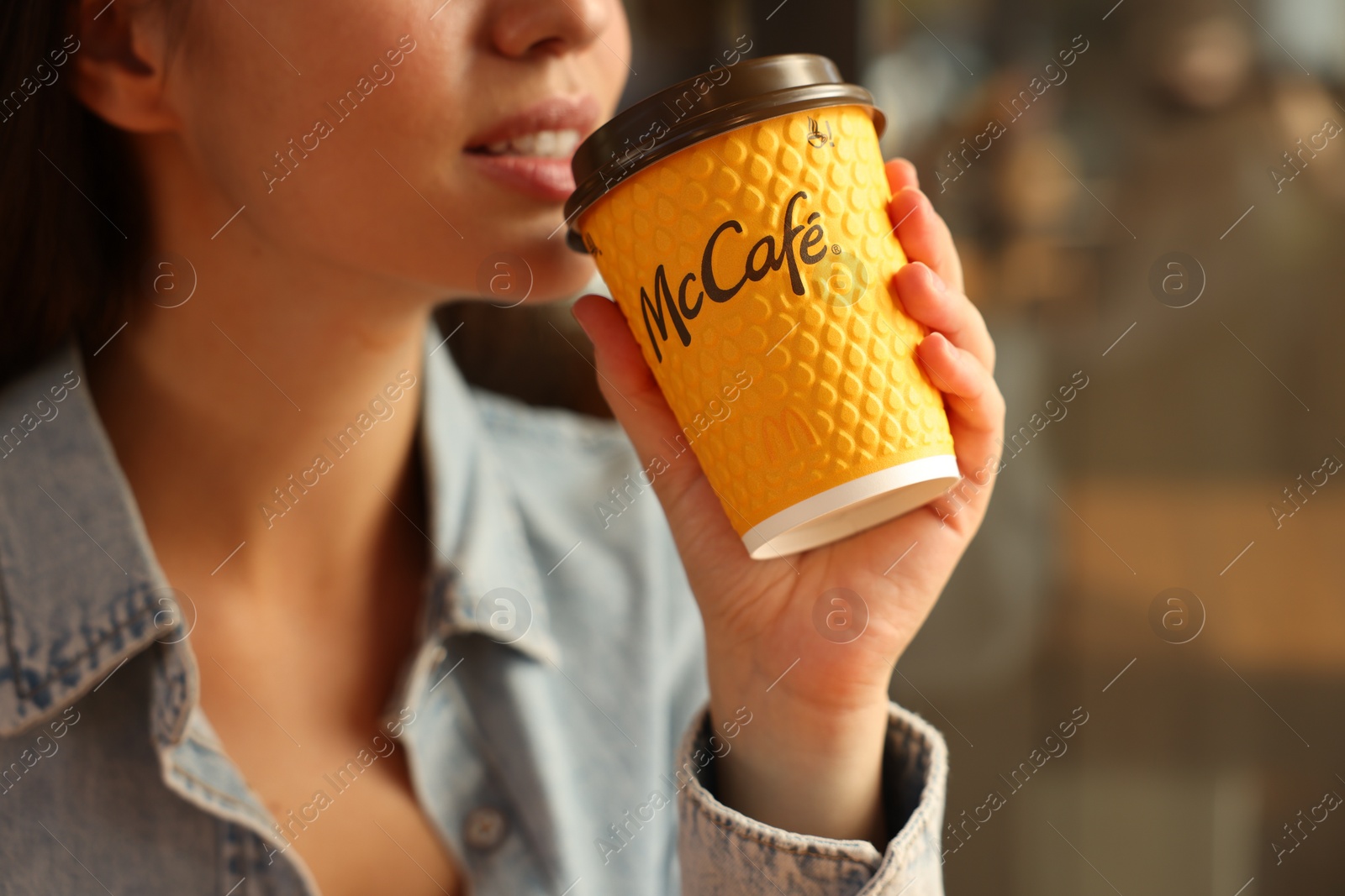 Photo of Lviv, Ukraine - September 26, 2023: Woman with hot McDonald's drink in cafe, closeup. Space for text