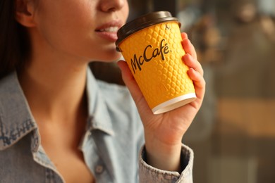Photo of Lviv, Ukraine - September 26, 2023: Woman with hot McDonald's drink in cafe, closeup. Space for text
