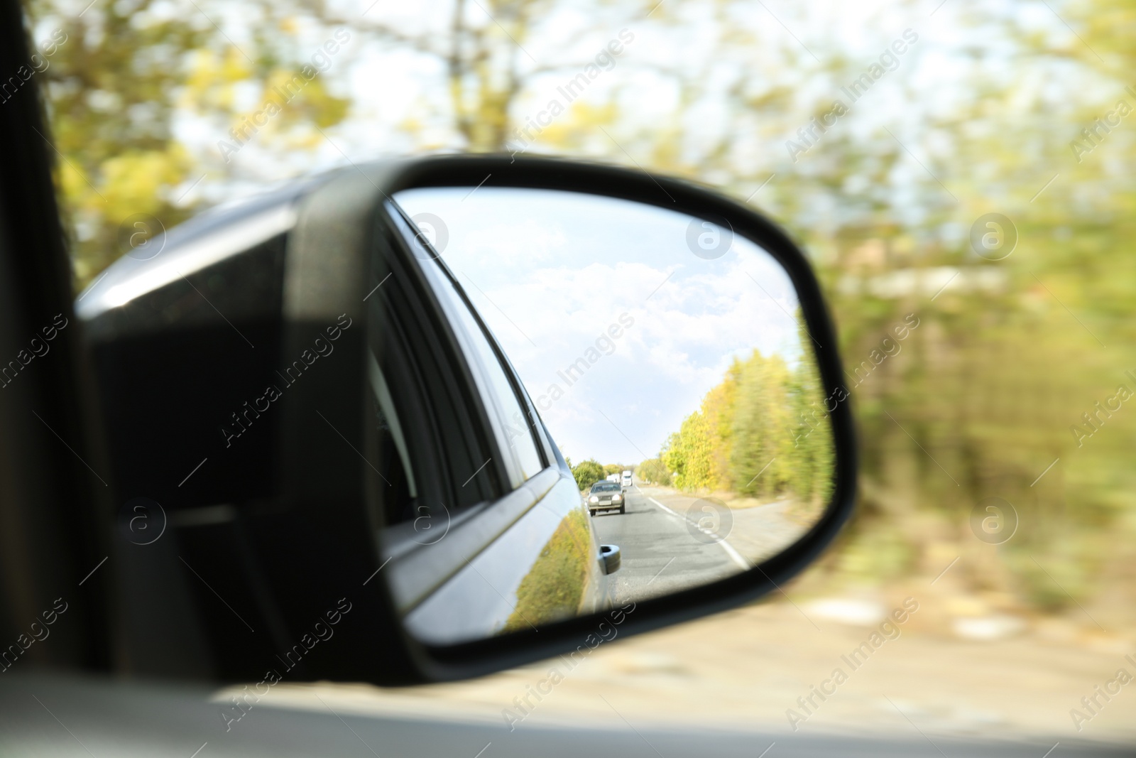 Photo of Closeup of car side rear view mirror on sunny day