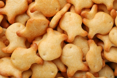 Photo of Delicious goldfish crackers as background, closeup view