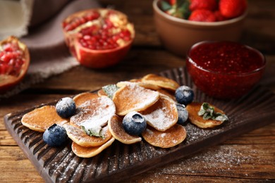 Photo of Cereal pancakes with blueberries and powdered sugar on wooden table