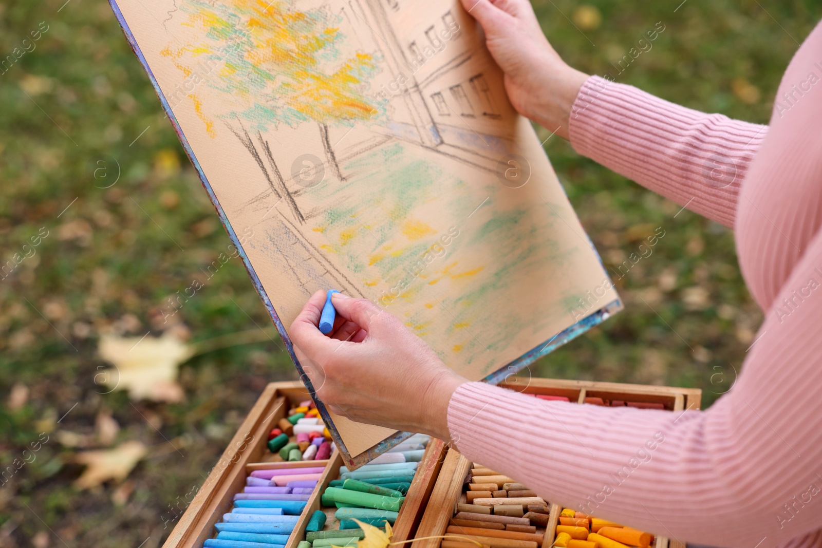 Photo of Woman drawing with soft pastels outdoors, closeup