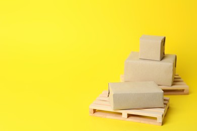 Wooden pallets and boxes on yellow background, space for text
