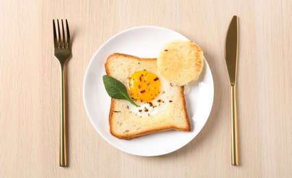 Tasty toast with fried egg served on wooden table, flat lay