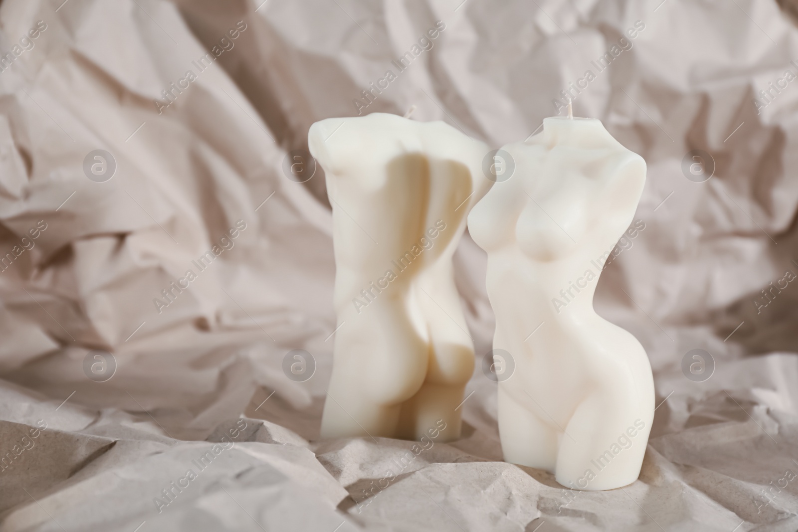 Photo of Beautiful male and female body shaped candles on crumpled paper