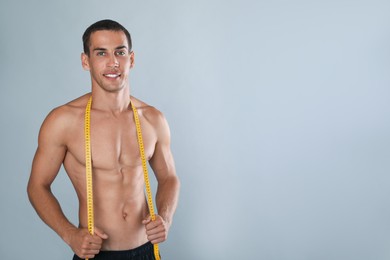 Photo of Handsome shirtless man with slim body and measuring tape on grey background. Space for text