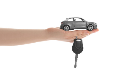 Photo of Woman holding key and miniature automobile model on white background, closeup. Car buying