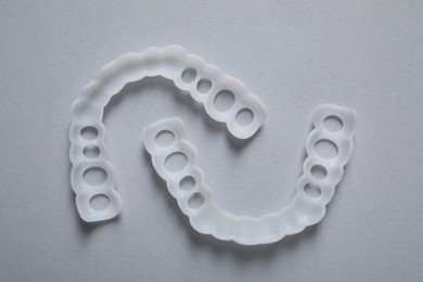 Photo of Dental mouth guards on grey background, flat lay. Bite correction