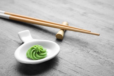 Photo of Plate with swirl of wasabi paste and chopsticks on grey table