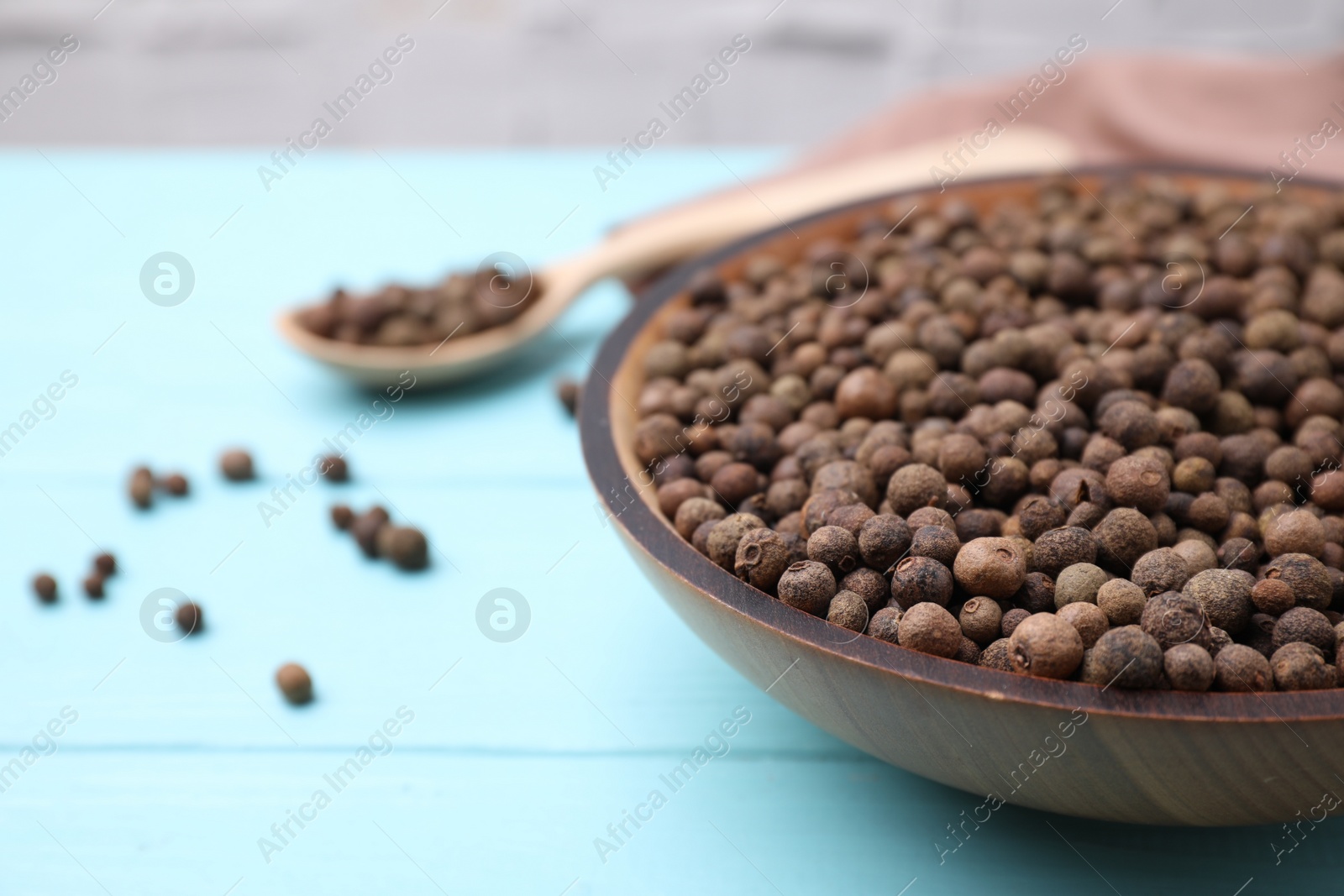 Photo of Peppercorns on light blue wooden table, closeup