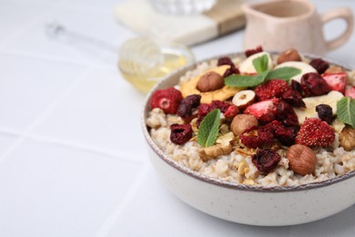 Photo of Oatmeal with freeze dried fruits, nuts and mint on white wooden table, closeup. Space for text