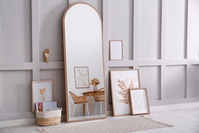 Light room interior with large mirror, beautiful pictures and pouf near wall