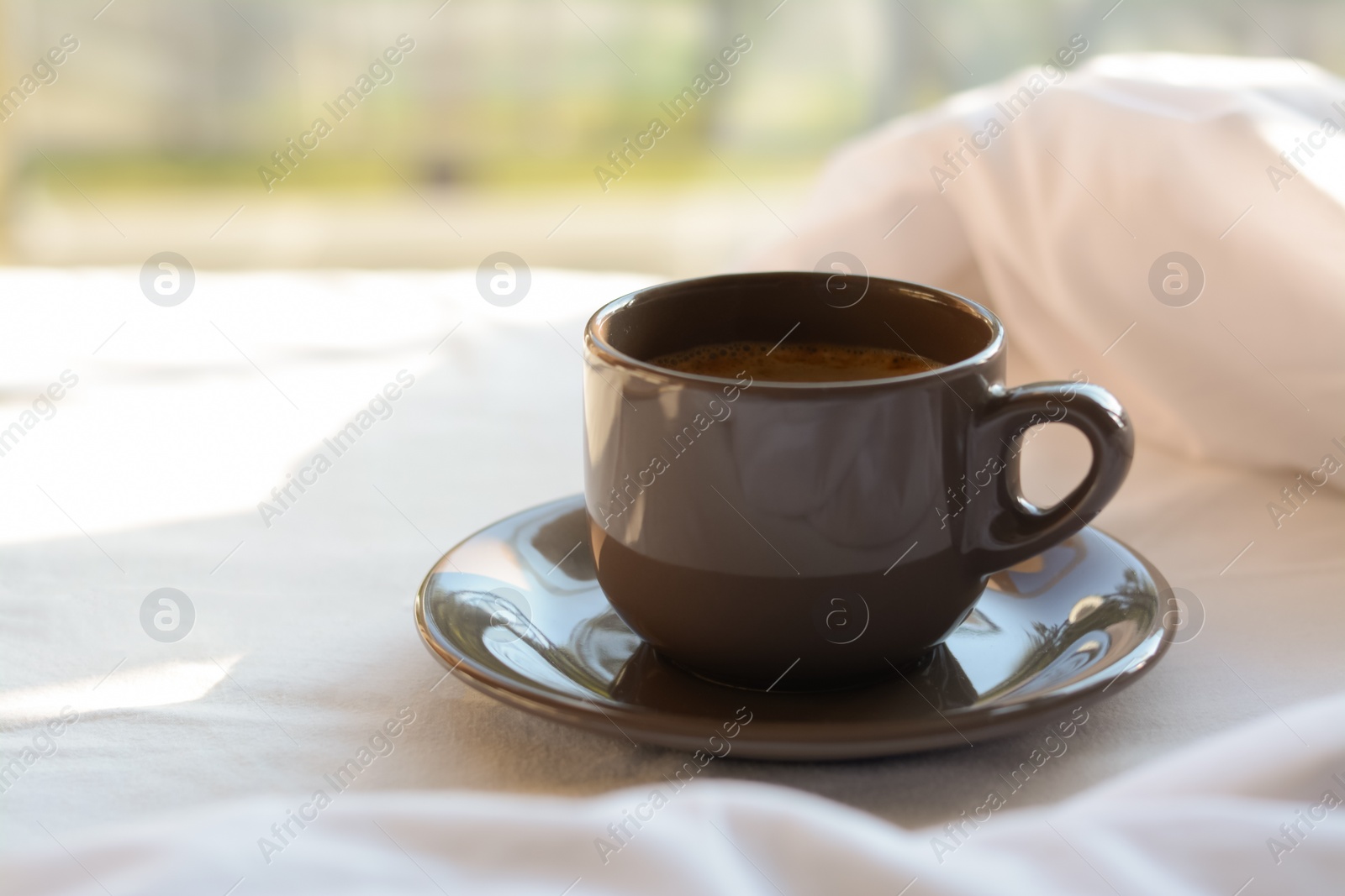 Photo of Cup of aromatic morning coffee on bed