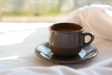 Cup of aromatic morning coffee on bed